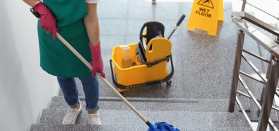 Young woman with mop cleaning stairs